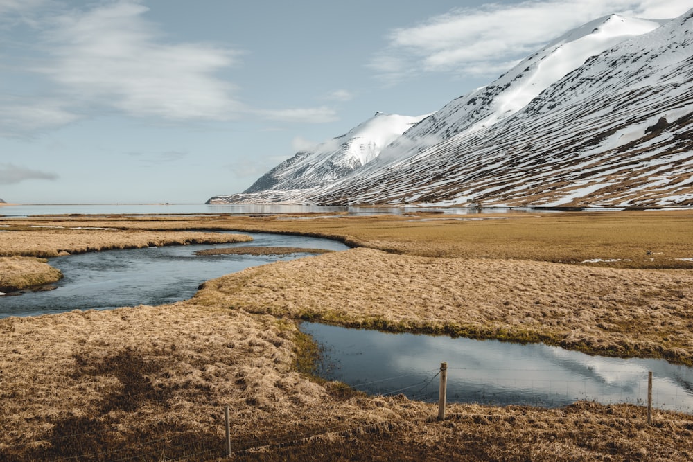 a river running through a dry grass covered field