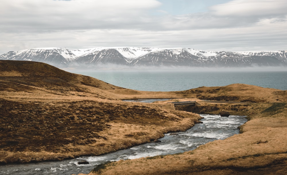 a stream running through a grass covered valley