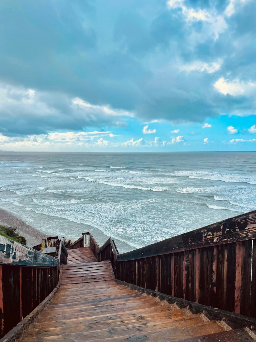 a wooden staircase leading to the beach with a view of the ocean