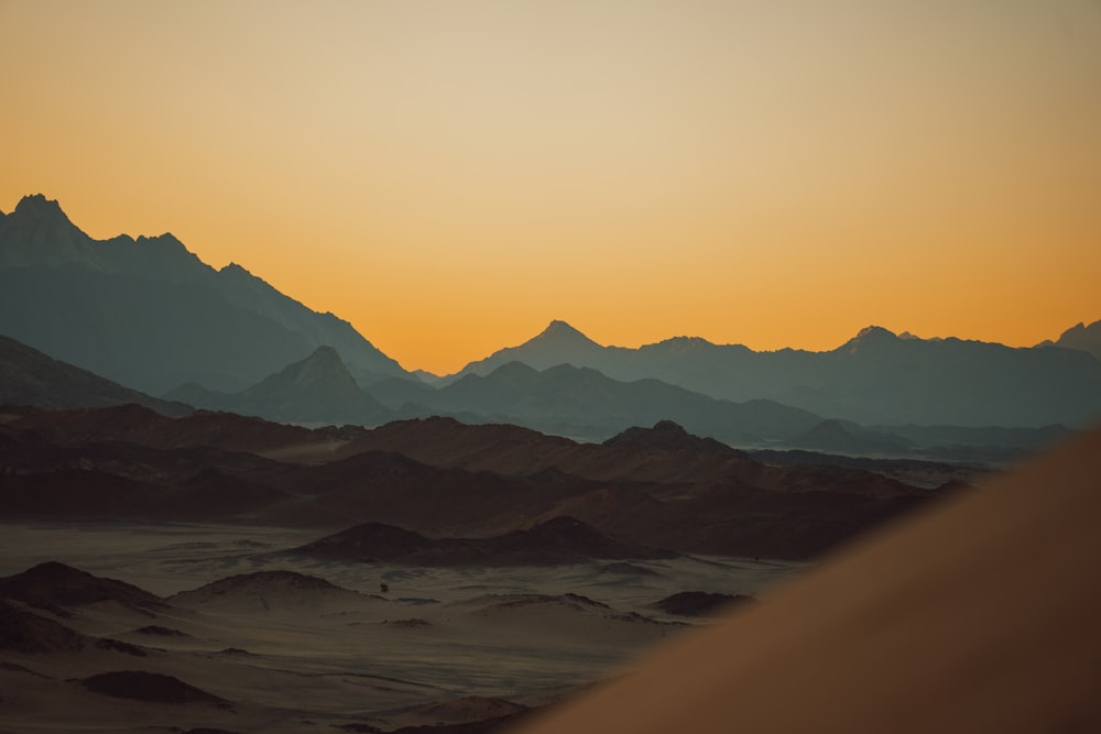 the sun is setting over the mountains in the desert