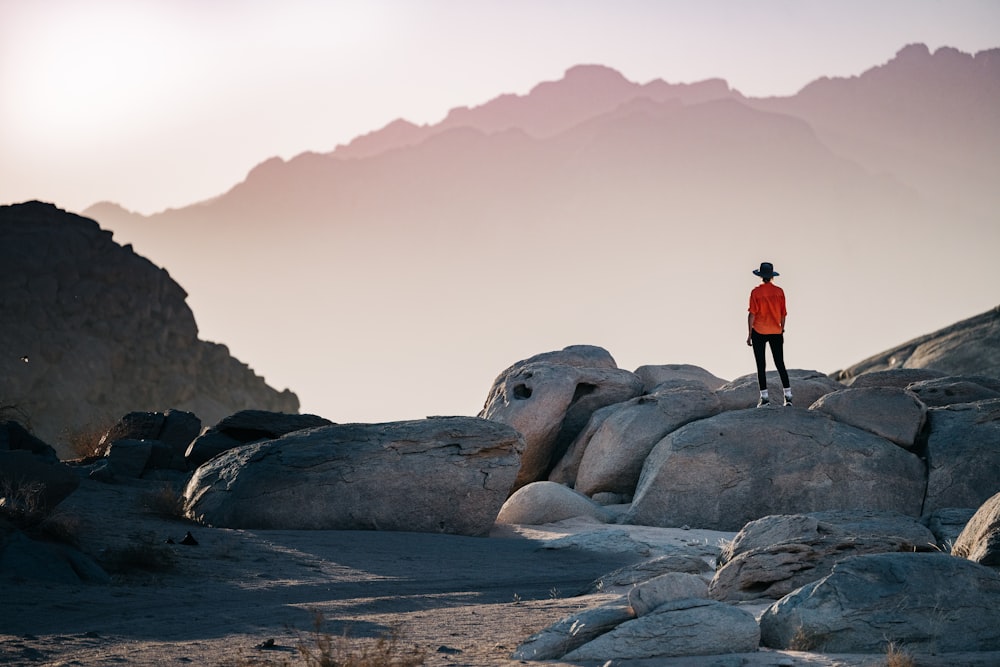 une personne debout au sommet d’un gros rocher