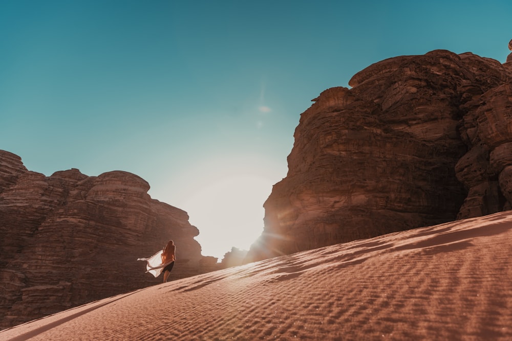 a person standing in the sand near some rocks