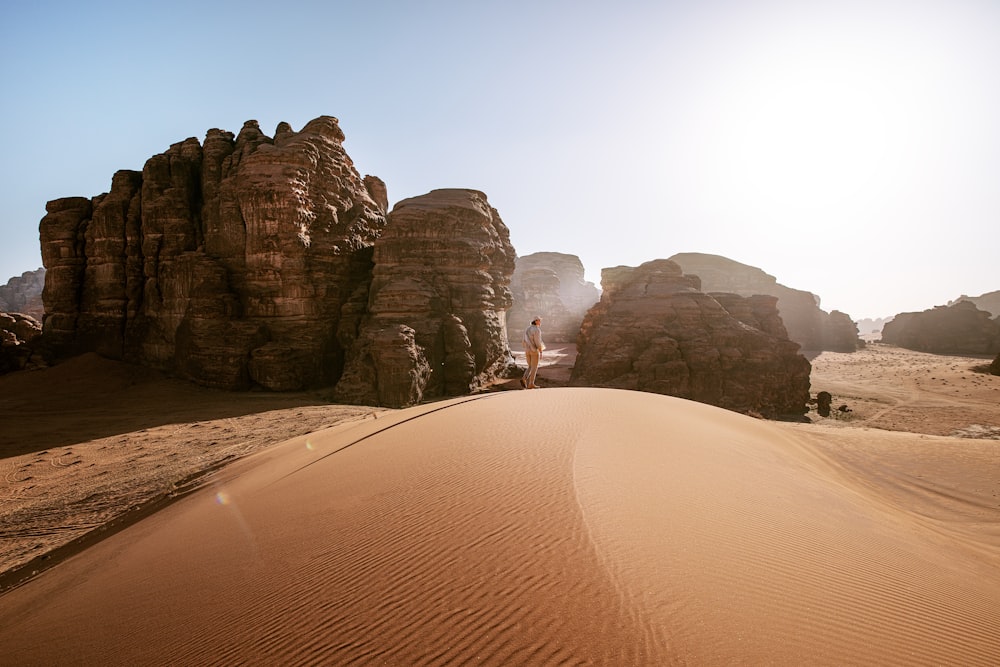 una persona in piedi in cima a una duna di sabbia