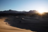 a person is walking in the desert at sunset