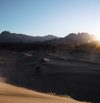 a person is walking in the desert at sunset