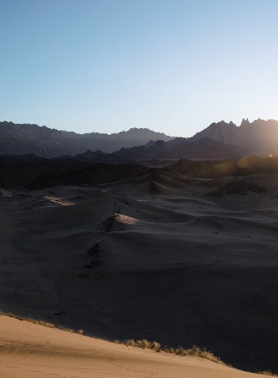 a person is walking in the desert at sunset