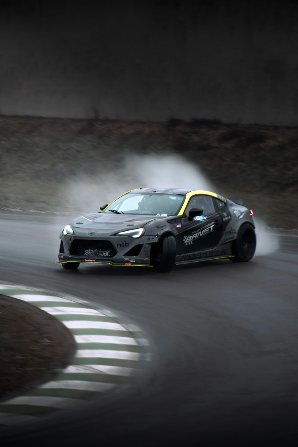 a car driving on a race track with a lot of smoke coming out of it