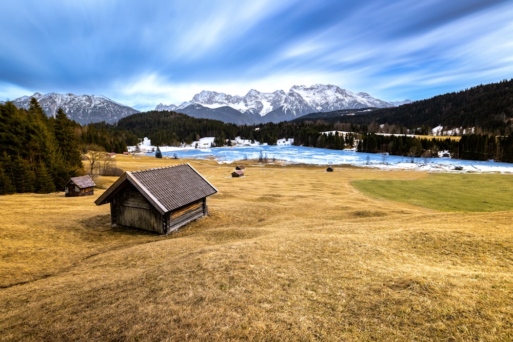 a small house in a field with mountains in the background