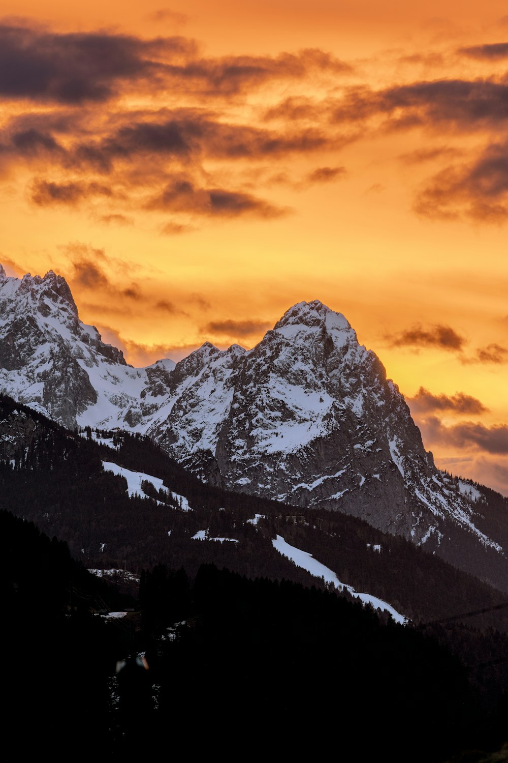 a mountain covered in snow under a cloudy sky