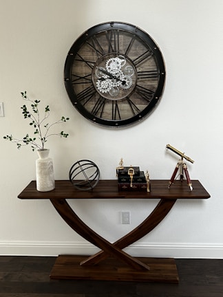 a wooden table with a clock on the wall