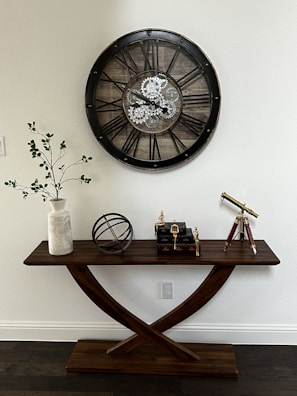 a wooden table with a clock on the wall