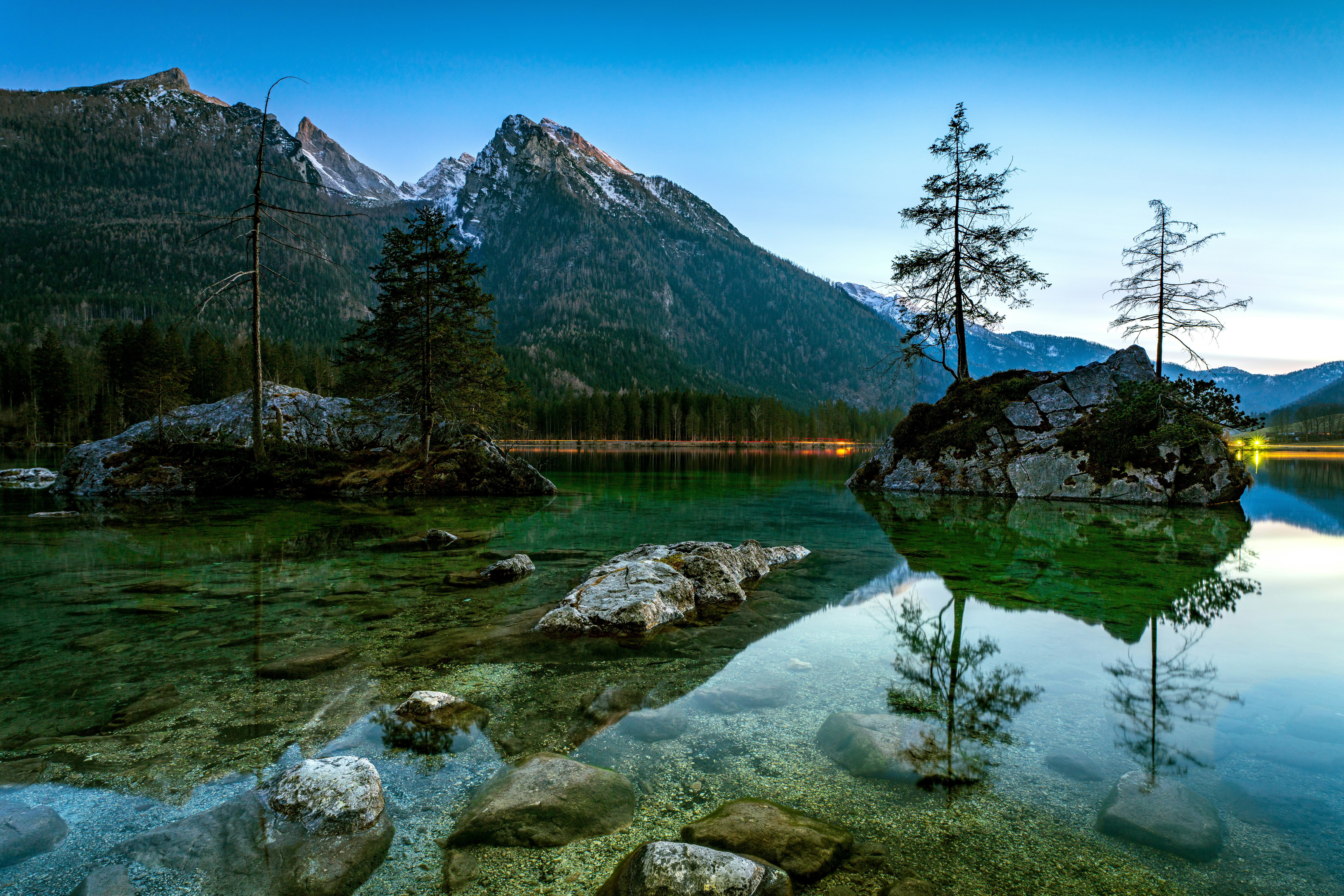 a body of water surrounded by mountains and trees, No matter what time of year you visit, the Hintesee is a great place to relax and enjoy the beauty of the Bavarian Alps.