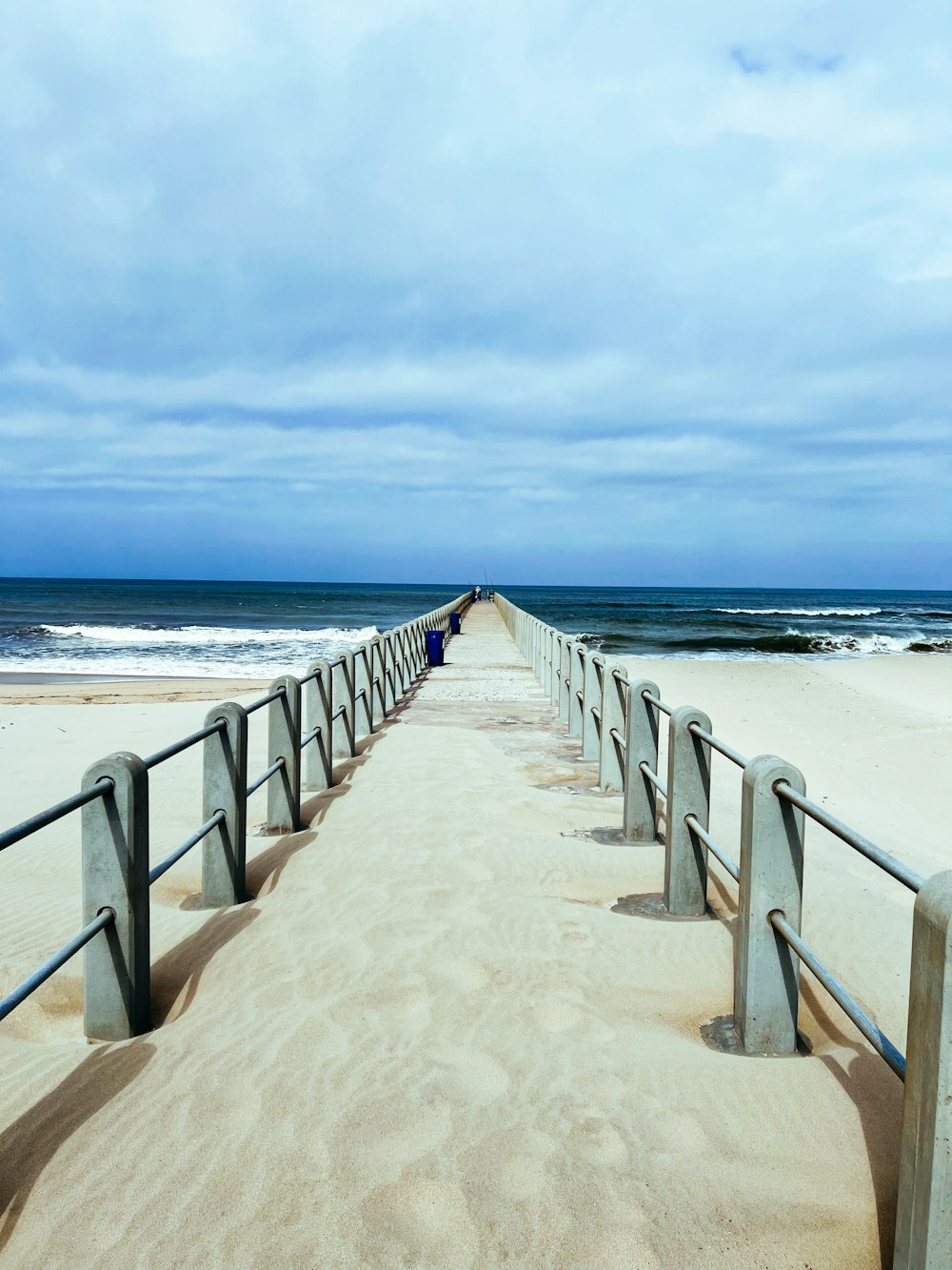 ein Strand mit einem langen Holzsteg, der zum Meer führt