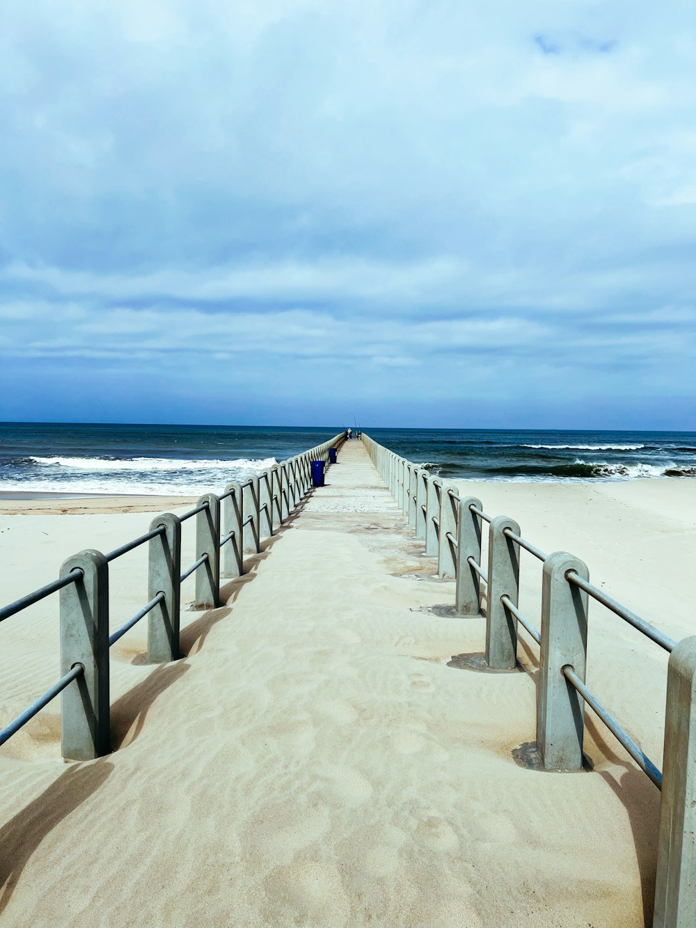 Una spiaggia con una lunga passerella di legno che conduce all'oceano