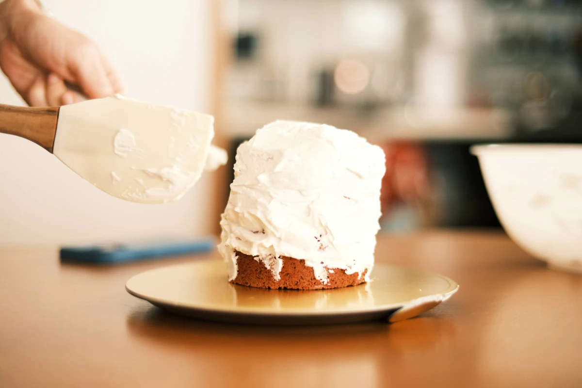Hands spreading icing on a cake
