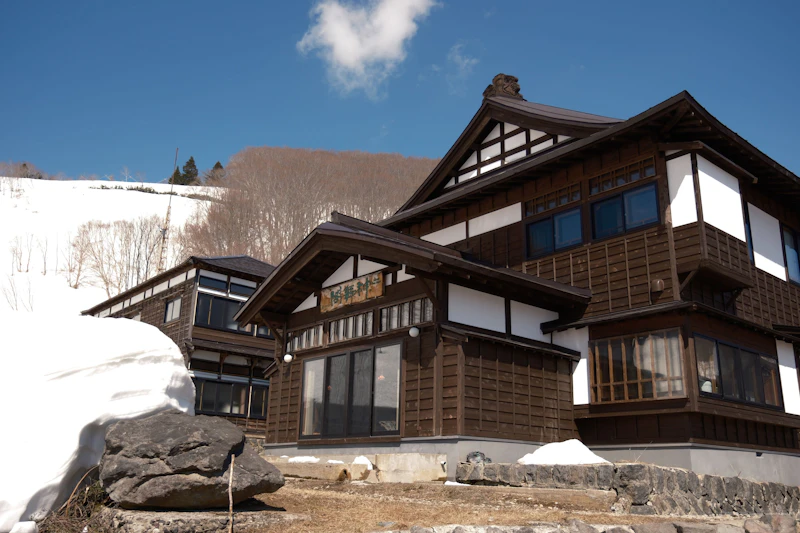 Sukayu Onsen Ryokan, a traditional Japanese inn building set on a snow-covered mountain slope in Aomori Prefecture, Japan — a classic example of a rural onsen ryokan exterior