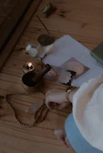 a table with a candle, a book, a necklace, and a cell phone