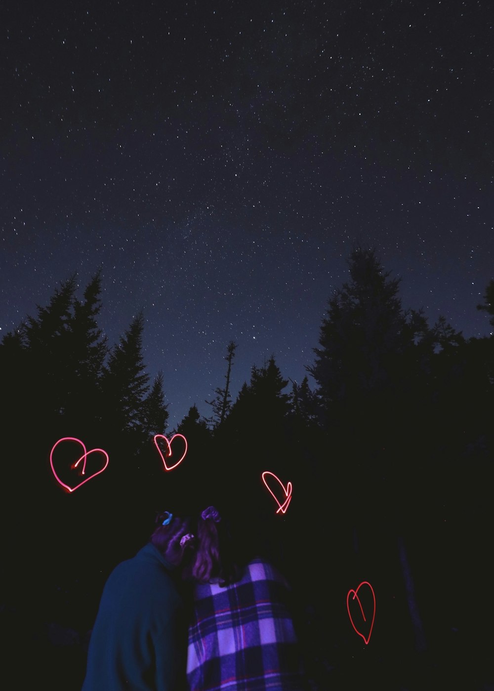 two people standing in the dark with hearts drawn on them