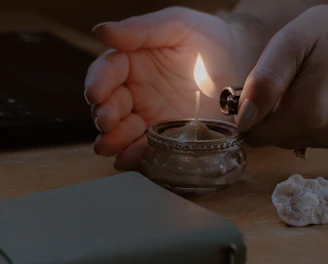 a person lighting a candle on a table