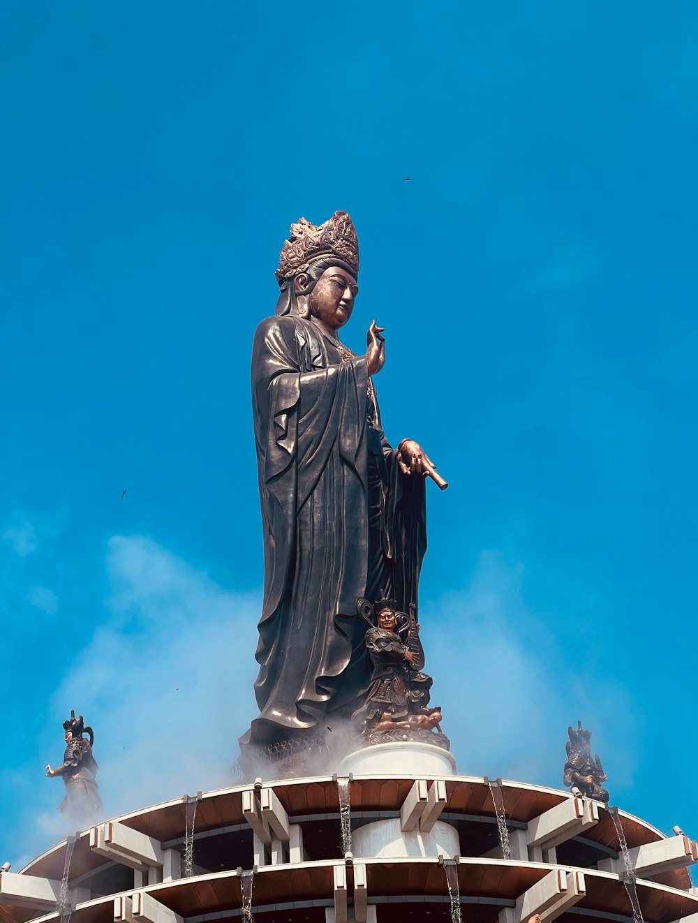 uma estátua no topo de um edifício com um céu azul no fundo