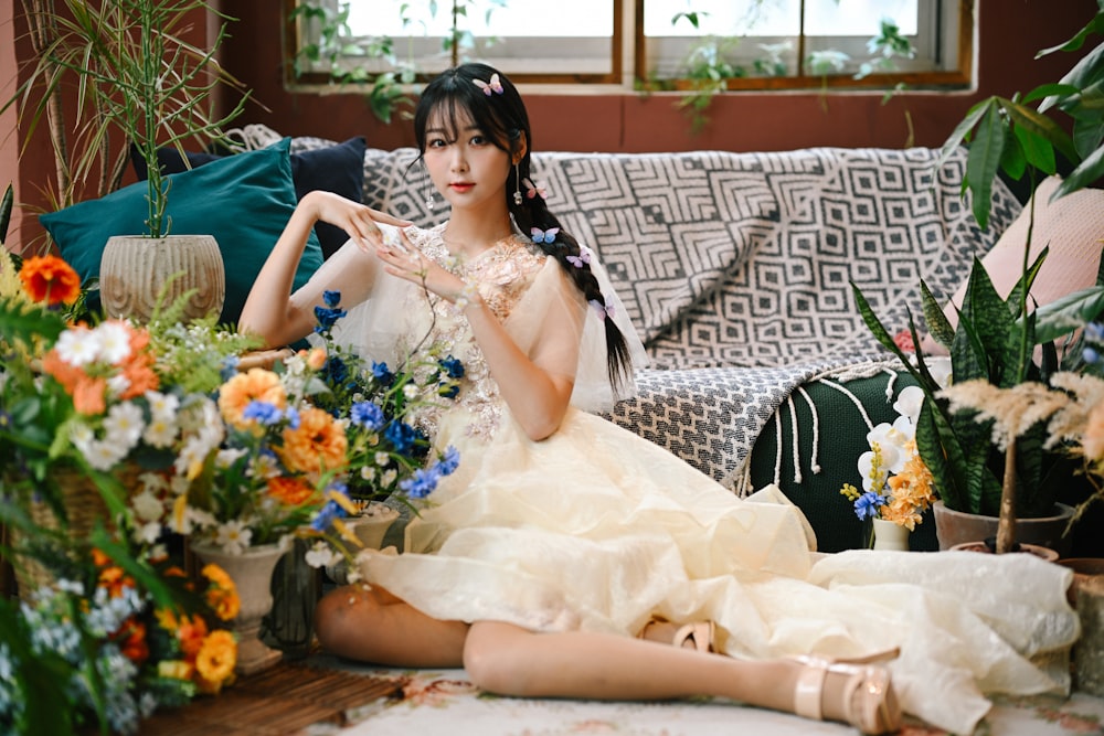 a woman sitting on a couch next to a bunch of flowers