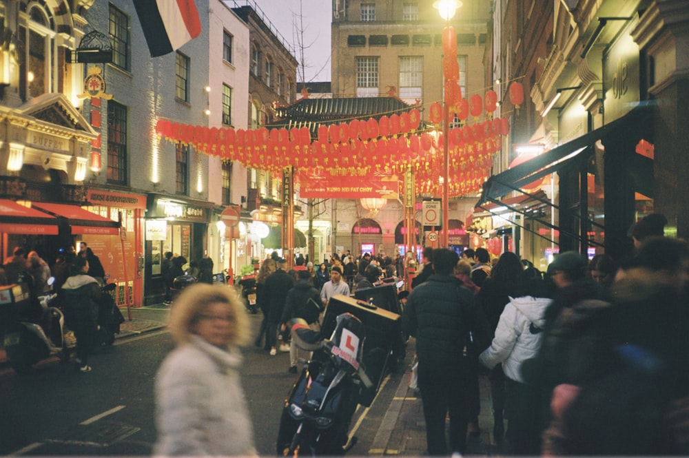 a group of people walking down a street next to tall buildings