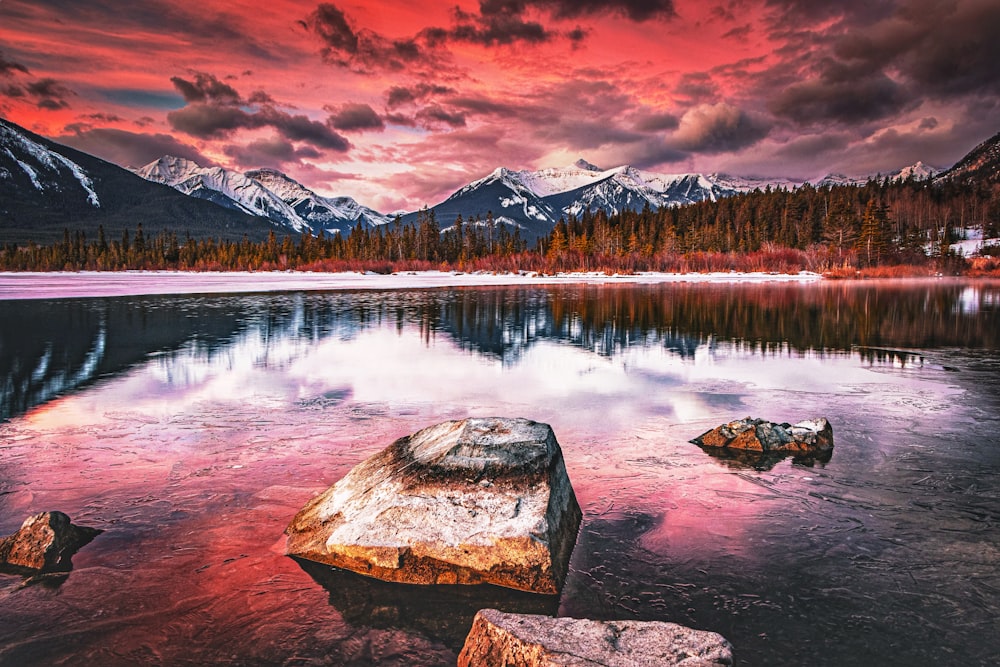 a lake with rocks in the water and mountains in the background