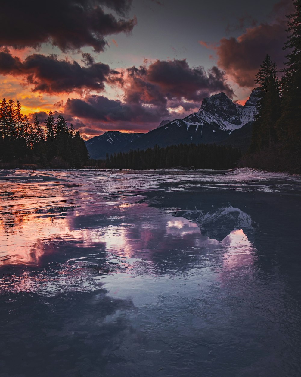 a beautiful sunset over a frozen lake with mountains in the background