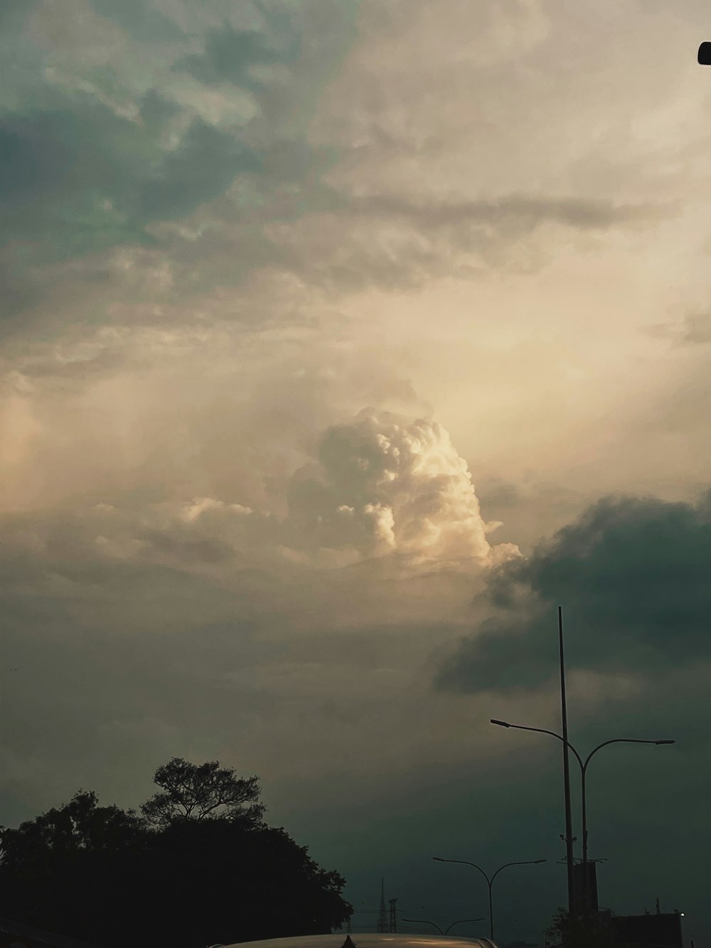 a cloudy sky with a street light and a car