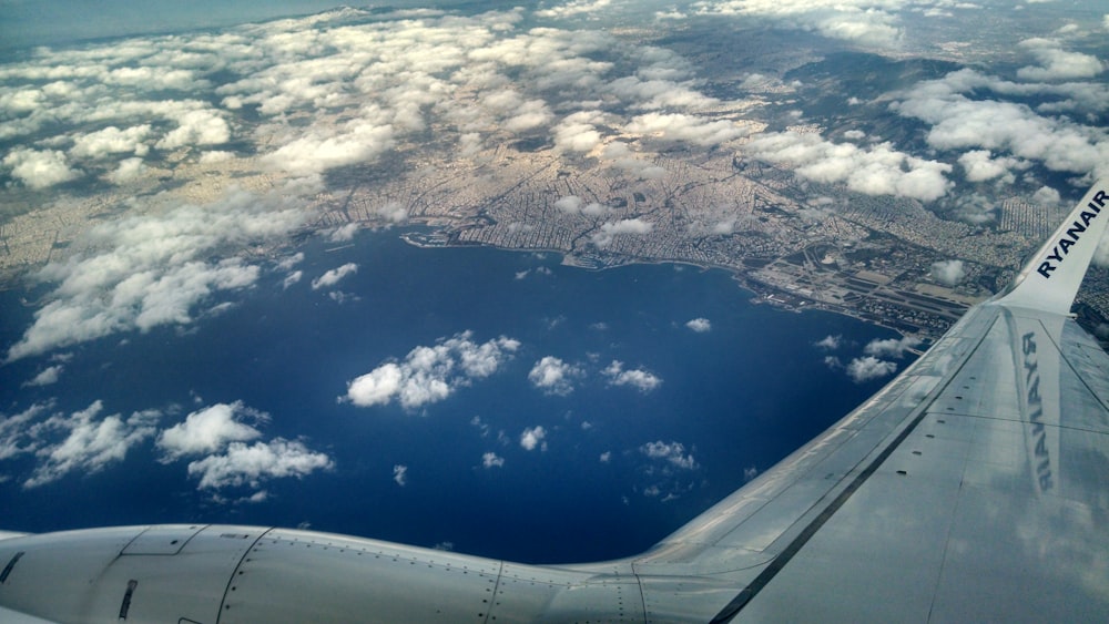 a view of the wing of an airplane flying over a body of water