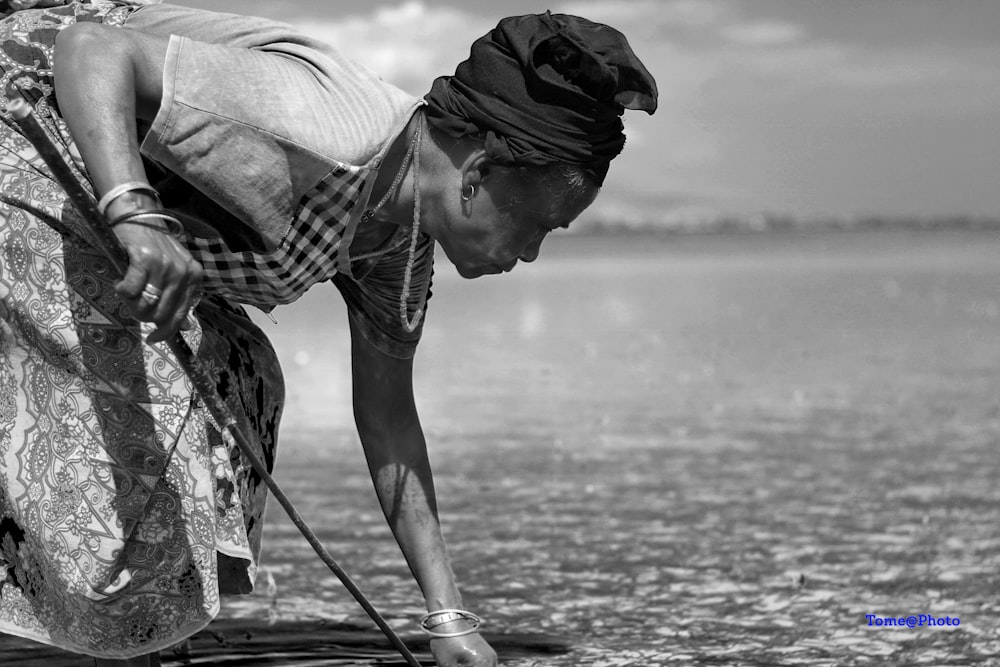 a man bending over to pick up something from the water