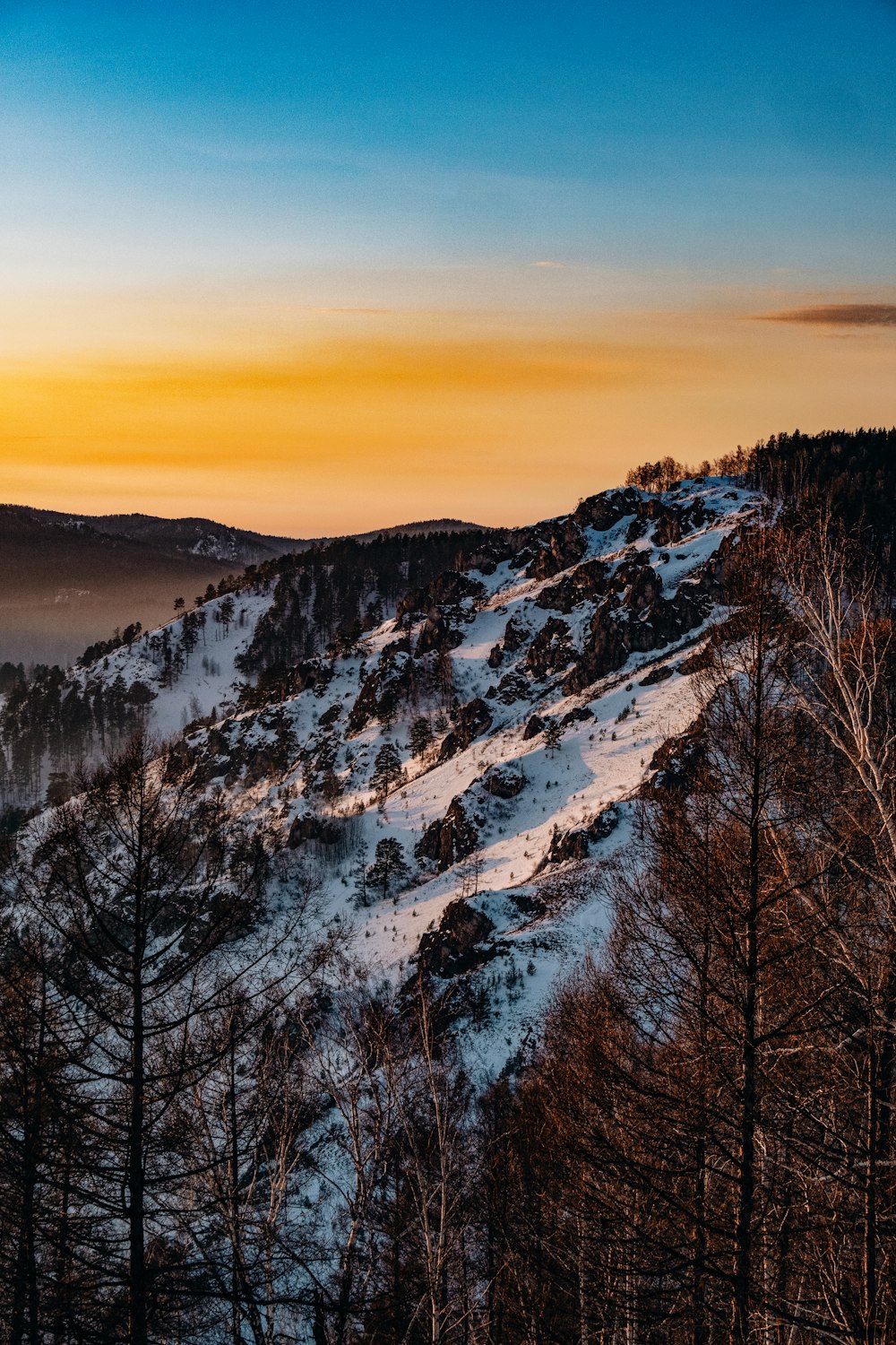 the sun is setting on a snowy mountain