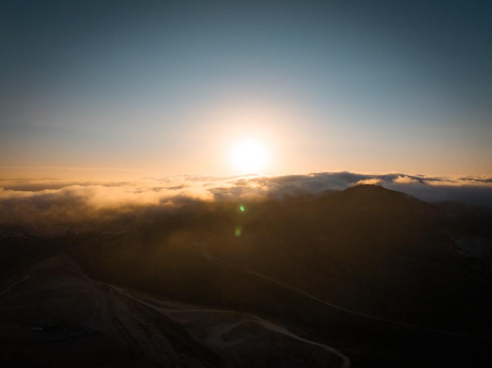 O sol está se pondo sobre as nuvens nas montanhas