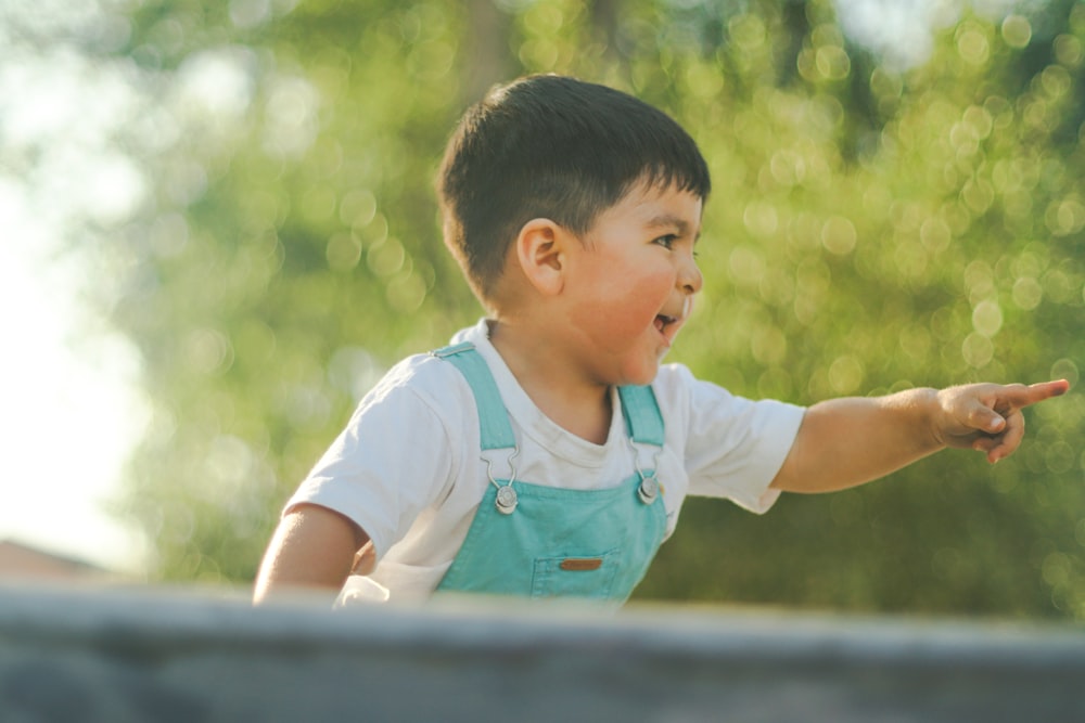 a little boy pointing at something in the air