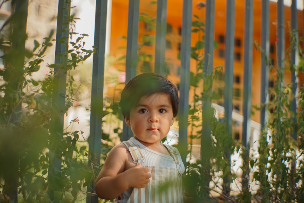 a young child standing in front of a fence