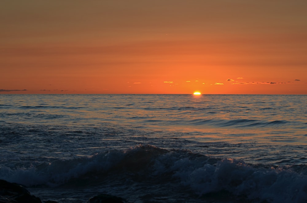 the sun is setting over the ocean with waves