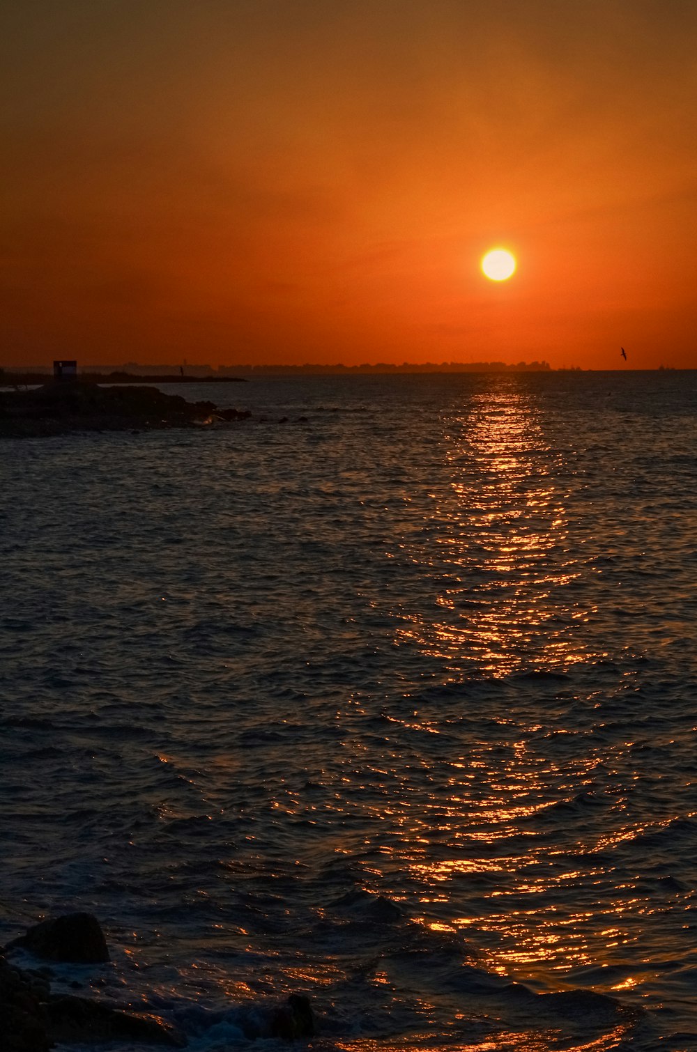 the sun is setting over the ocean with a boat in the distance