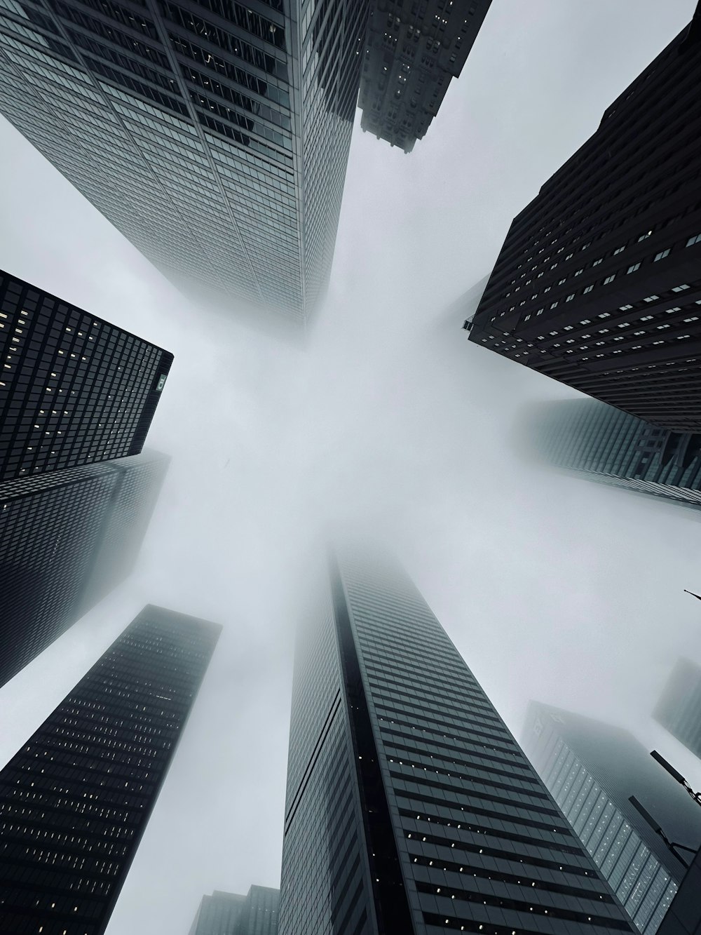 a group of tall buildings in the middle of a foggy sky