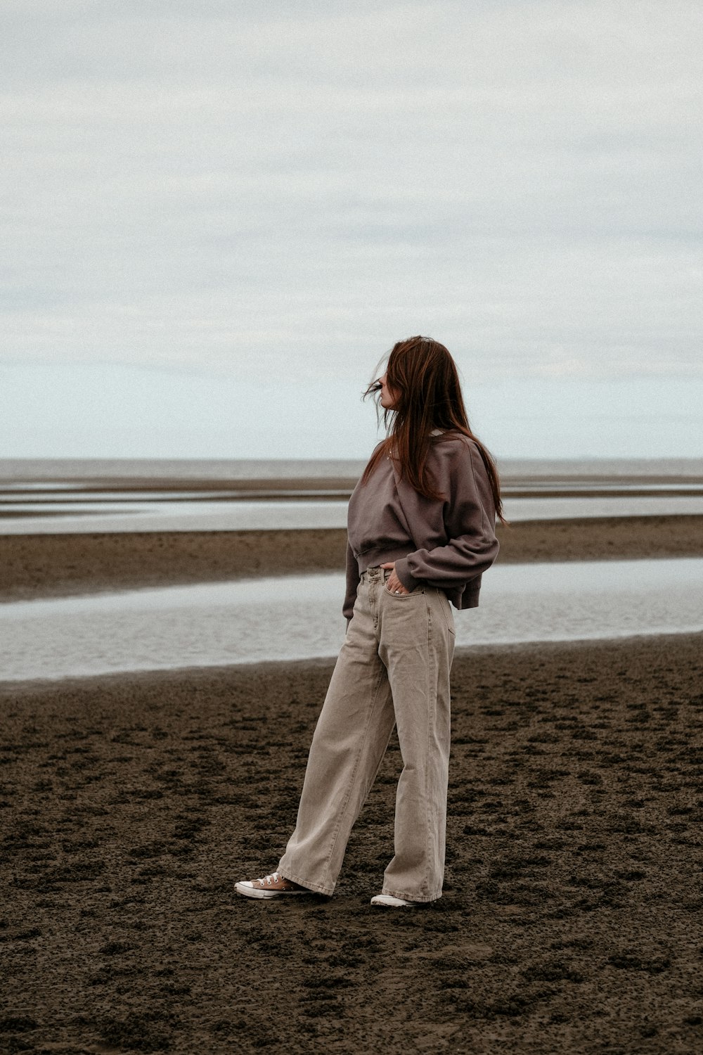 a woman standing on a beach next to a body of water