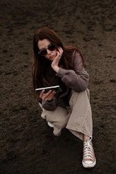 a woman sitting on the ground while talking on a cell phone