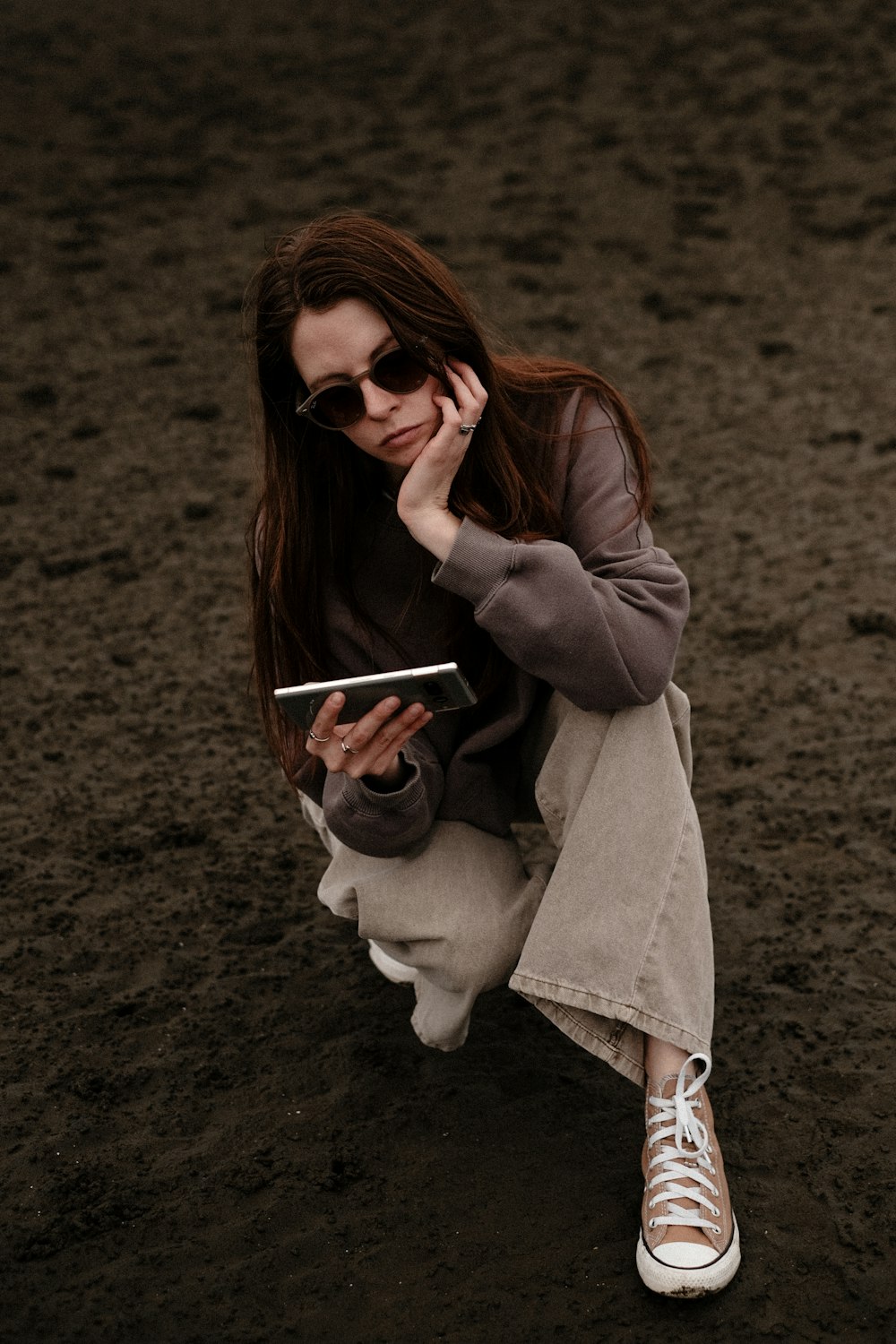 a woman sitting on the ground while talking on a cell phone