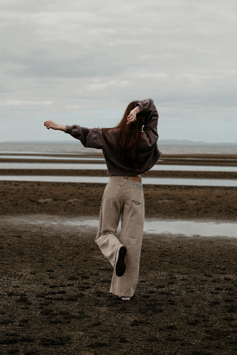 una donna in piedi su una spiaggia con le braccia tese