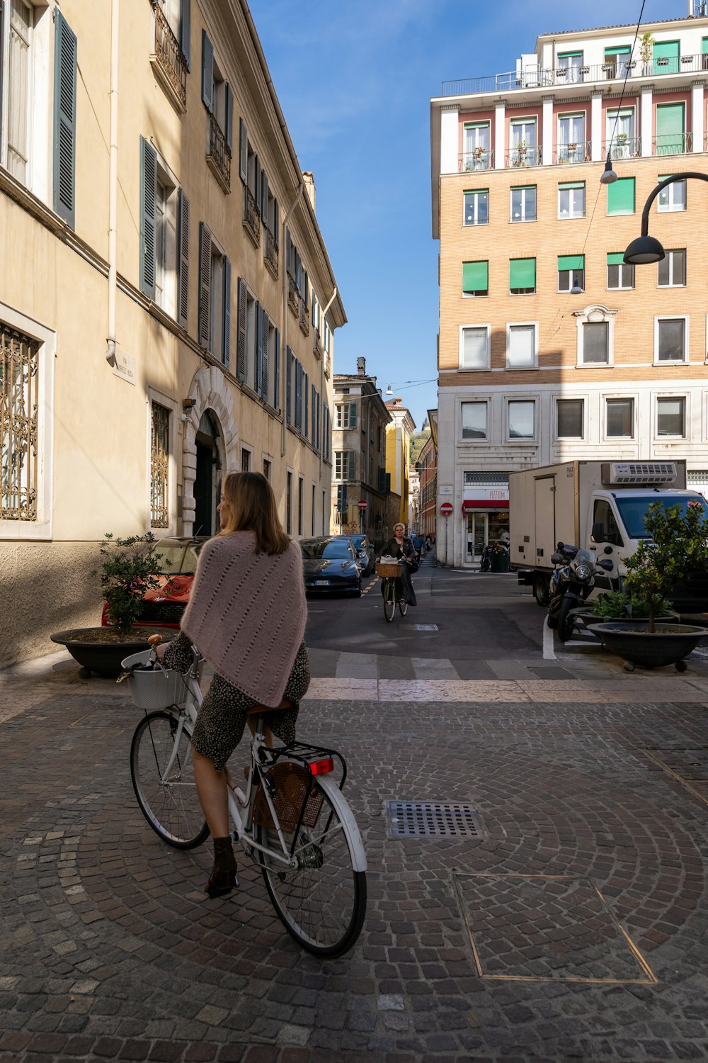 a woman riding a bike down a street next to tall buildings