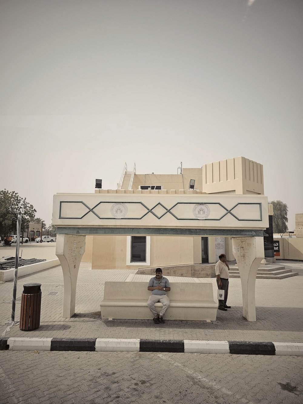 two men sitting on a bench in front of a building