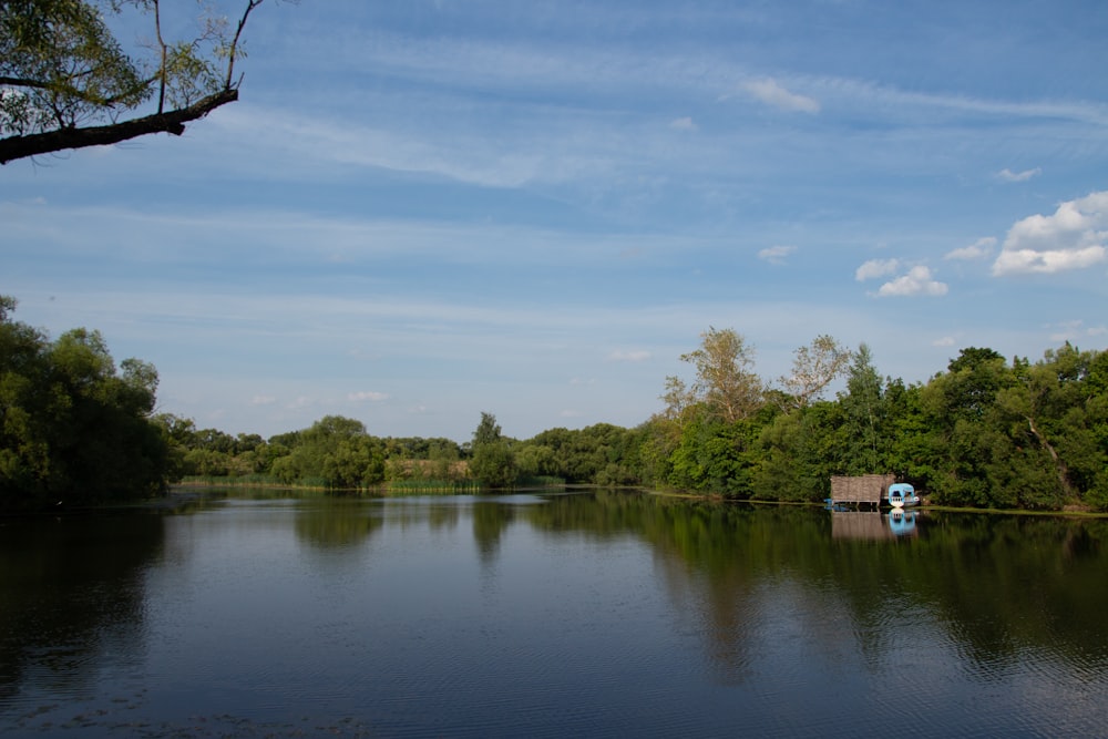 a body of water surrounded by trees and a blue sky