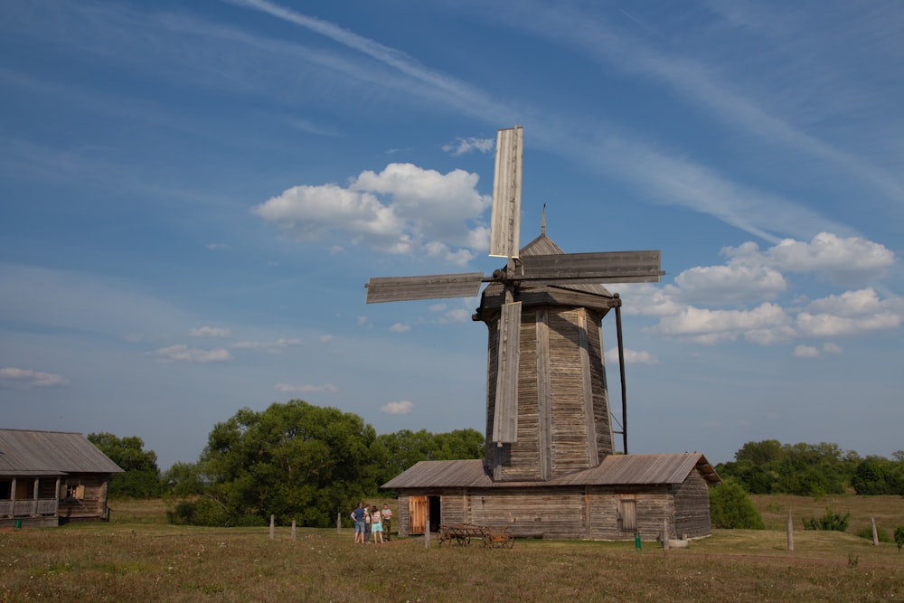 a windmill in a field with people standing around it