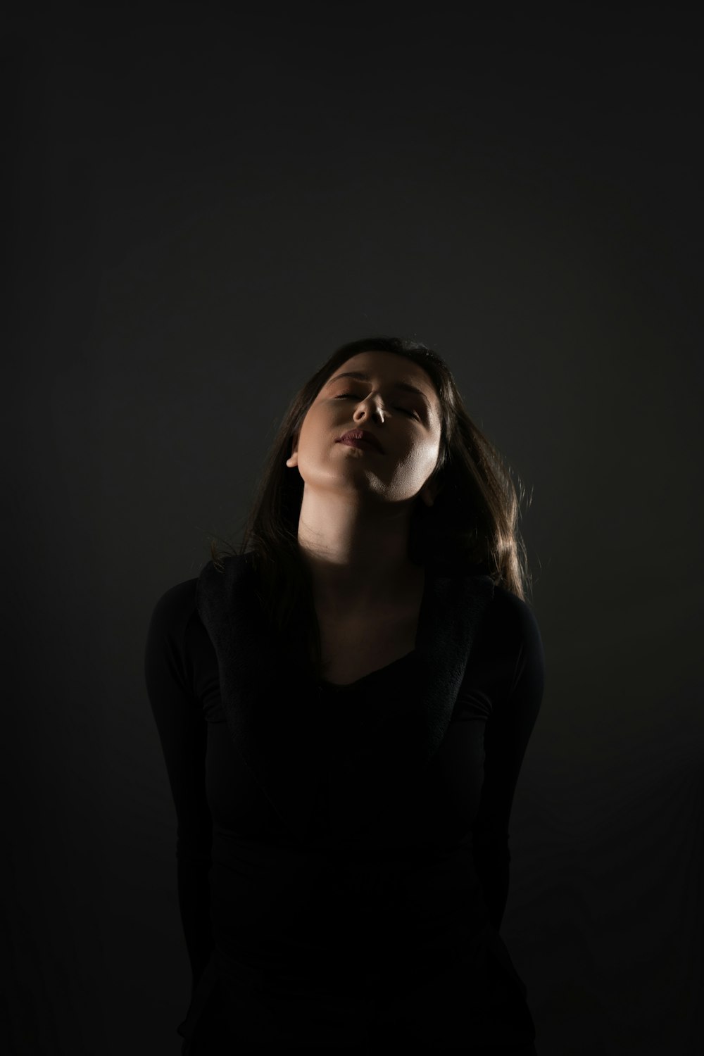 a woman standing in the dark with her eyes closed