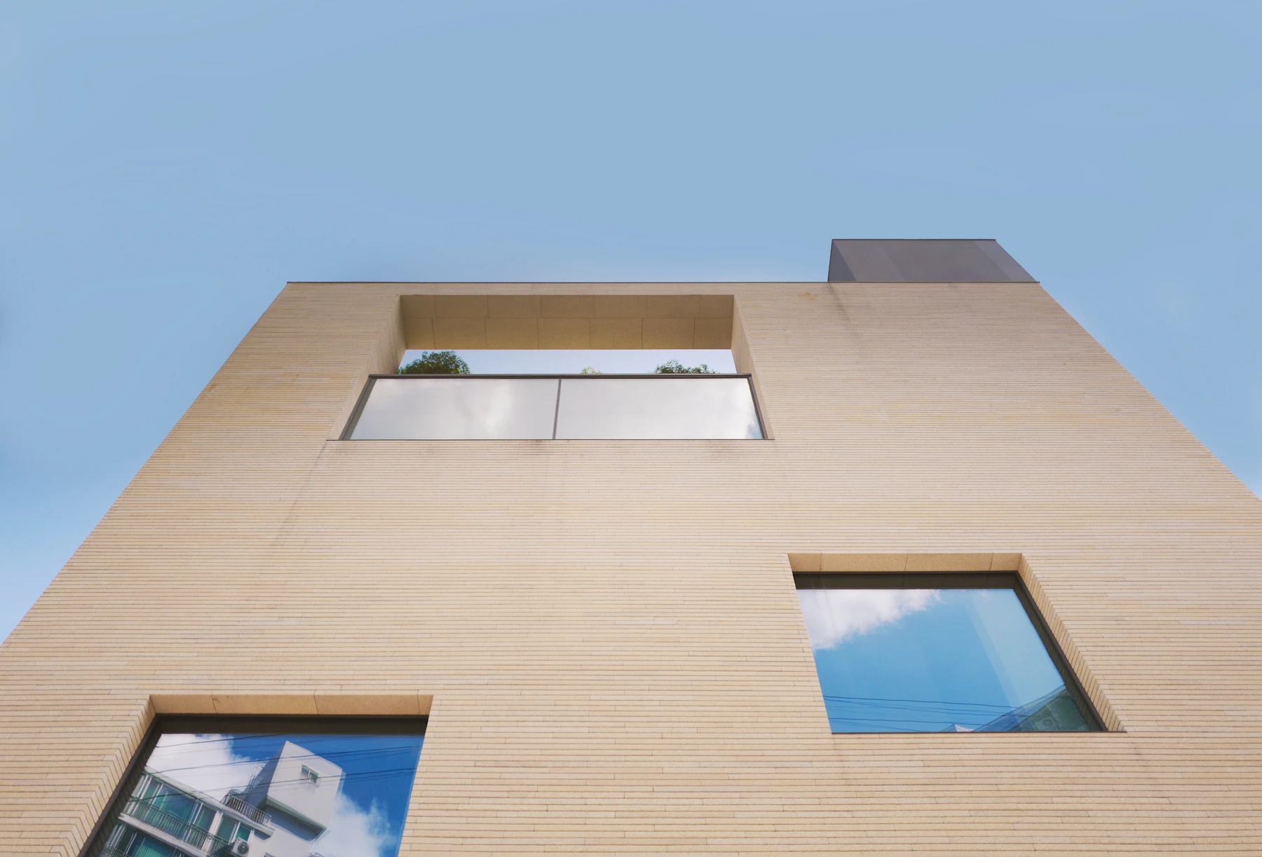 Fachada minimalista em tons claros com aberturas geométricas