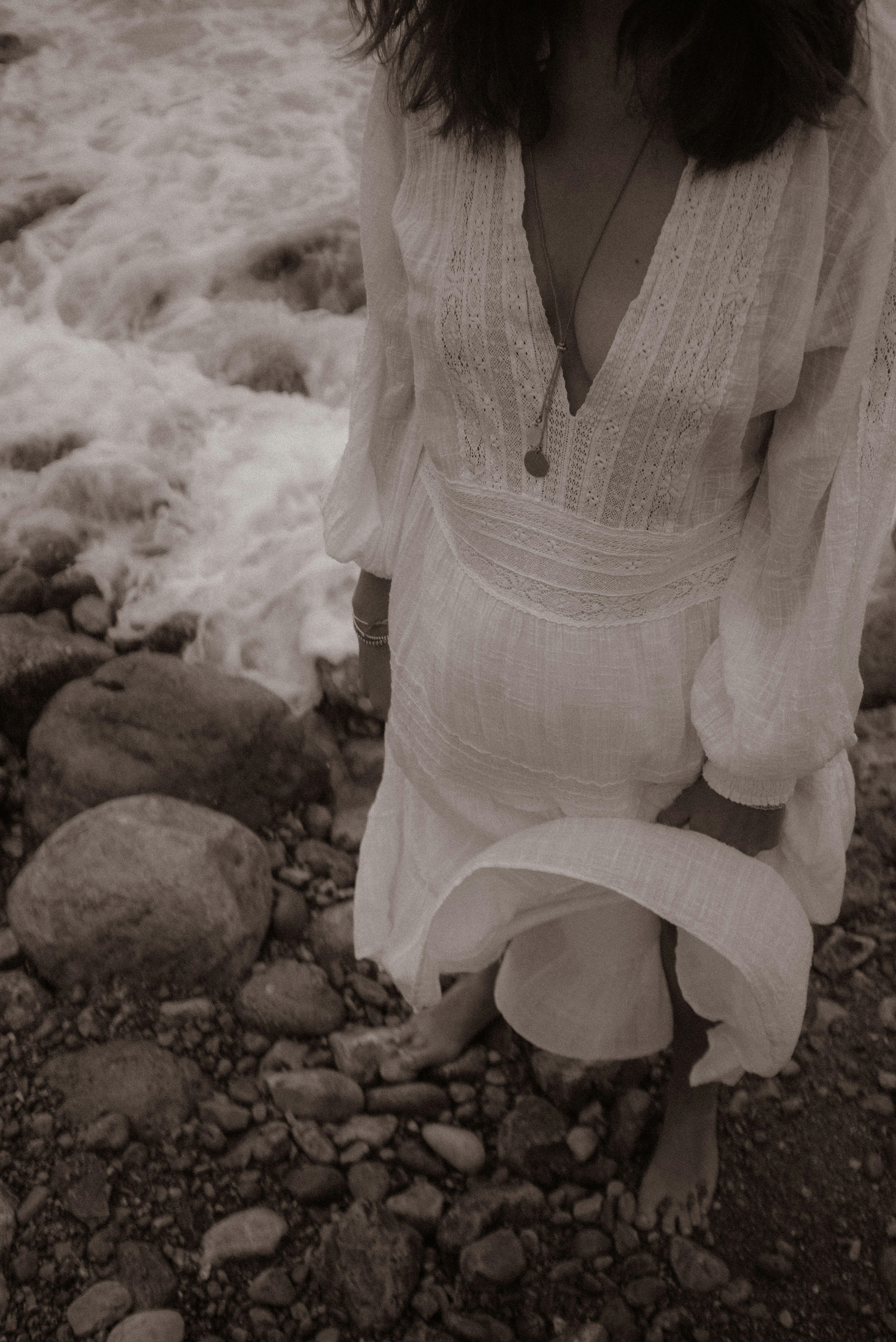 A woman standing on a rocky beach next to the ocean photo – Free ...