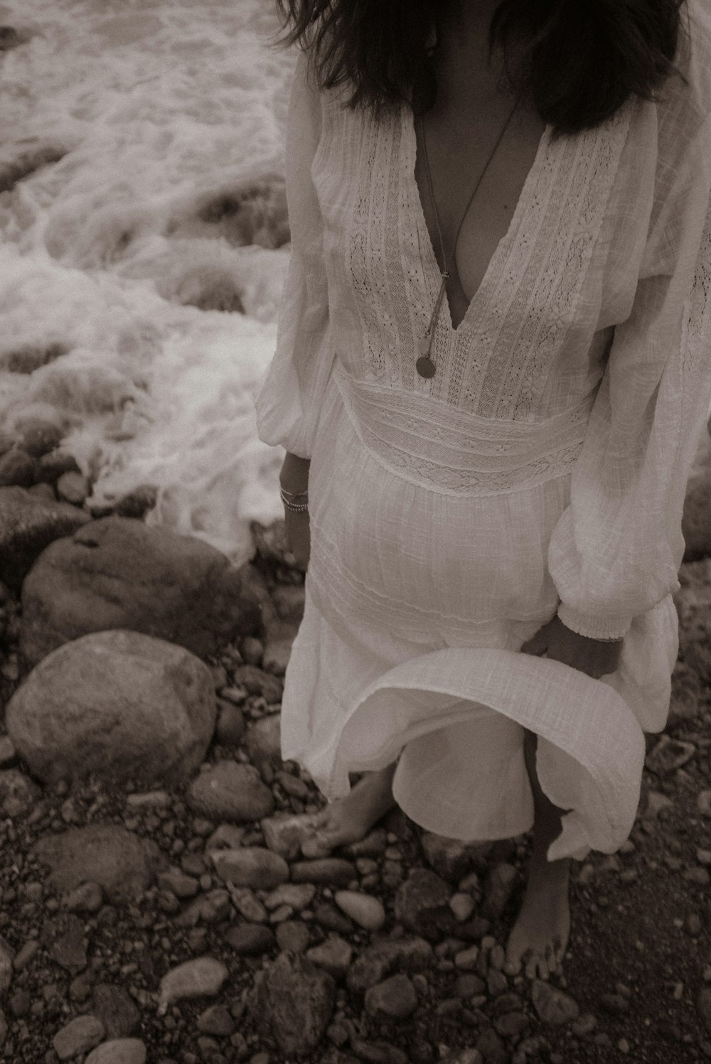 a woman standing on a rocky beach next to the ocean